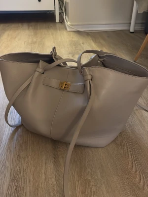 Beige shoppingväska från Gina Tricot - Shoppingväska från Gina i ljusbeige! Så fin och praktisk nu till sommaren. Den är har några fläckar på insidan samt att banden är lite slitna, annars har den använts varsamt😊