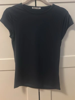 Mörkblå basic tight t-shirt från Zara - En enkel mörkblå t-shirt från Zara med rund halsringning och korta ärmar. Tillverkad i mjukt och stretchigt material som sitter skönt mot kroppen. Perfekt att matcha med jeans eller kjol för en clean look. Säljer då den tyvärr inte kommer till användning pga att den är för stor för mig. Pris kan diskuteras!💕