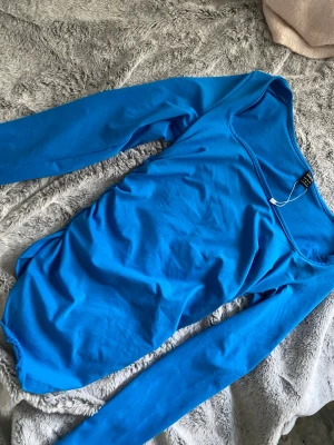 Blå långärmad tröja - Snygg blå tröja från shein med lång ärm och rundad halsringning. Tillverkad i mjukt material som sitter skönt mot kroppen. Perfekt att styla med jeans eller kjol för en trendig look. Den är scrunchad på sidan. Inte använt någon gång 