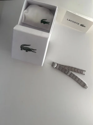 LACOSTE ARMBAND  - ETT LACOSTE ARMBAND HELT OANVÄNT.SKRIV OM DU VILL HA BÄTTRE BILDER.PRISET KAN DISKUTERAS.