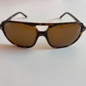 Ray-Ban solglasögon - Ray-Ban solglasögon med bruna glas. Kommer med ett svart fodral. Inköpta förra våren, sparsamt använda och i väldigt bra skick. Kvitto finns. 