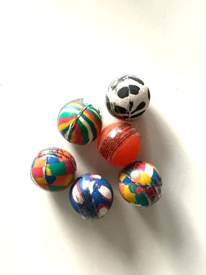 Färgglada studsbollar i gummi - Sex stycken små studsbollar i olika färger och mönster. Bollarna är runda och tillverkade i gummi, med bland annat randiga, rutiga och fotbollsinspirerade motiv. Perfekta för lek eller samling.