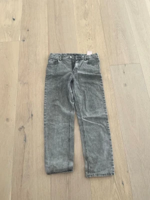 Grå raka jeans från LMTD - Snygga grå raka jeans från LMTD med klassisk femficksdesign och dragkedjegylf. Jeansen har en tvättad look och är perfekta för en avslappnad stil. Materialet är bomull med en mjuk känsla. Passar dig som gillar en trendig och enkel vibe.