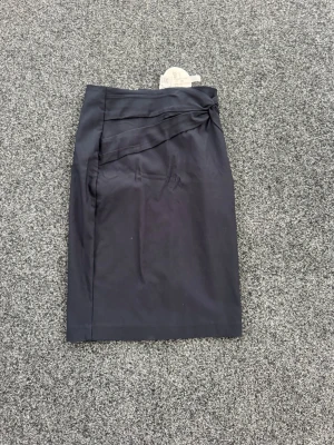 Svart pennkjol med rosettdetalj - Stilren svart pennkjol från orsay med snygg rosettdetalj i midjan. Kjolen har en klassisk, rak form och är perfekt för en dressad look. Tillverkad i ett mjukt material som ger en bekväm passform. Passar till S också 