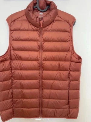 Rostbrun dunväst från Uniqlo - Snygg rostbrun dunväst från Uniqlo Ultra Light Down. Västen har hög krage, dragkedja framtill och quiltad design. Tillverkad i lätt och smidigt material med dunfyllning som håller dig varm utan att kännas tung.