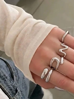 Set med fyra silver chunky ringar - Fyra ringar i silverfärgad metall med chunky och organiska former. Varje ring har en unik, vågig design som ger en modern och edgy känsla. Perfekt för dig som gillar statement-smycken och vill ha något som verkligen sticker ut.