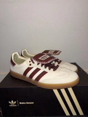 Adidas Wales Bonner - Ett par riktigt snygga Adidas Wales Bonner i en créme vit färg med detaljer av vinrött. Dom är i väldigt bra skick och har endast används ett par gånger! Skriv om du har frågor eller vill ha fler bilder!