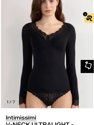 Svart spetsdetaljerad topp Intimissimi - Svart långärmad topp från Intimissimi med v-ringning och spetsdetaljer vid halsringning och ärmslut. Tunn och följsam modell som sitter snyggt mot kroppen och ger en elegant look.