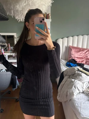 Svart ribbad bodycon klänning - Tajt svart ribbad klänning med lång ärm och rund halsringning. Klänningen har en kort, figurnära passform och djup rygg. Perfekt för dig som gillar en enkel men snygg stil.(prislappen är kvar)