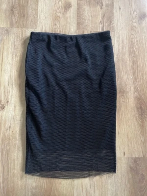 Kjol med fiskenät - Unik längre kjol med fiskenätsmönster som slutar strax under knäna. Köpte second hand men har själv aldrig använt. Är i mycket fint skick och går inte att se på den att den varit använd tidigare.