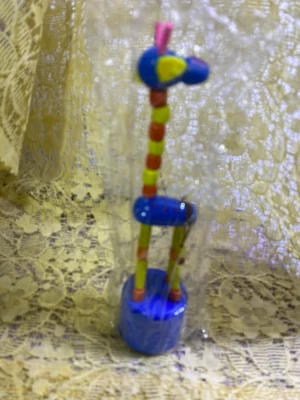 Färgglad träfigur giraff - En lekfull och färgglad giraff i trä med blå, gul, rosa och orange detaljer. Figuren står på en blå rund bas och har rörliga leder. Perfekt som dekoration eller leksak. Säljs inplastad. 49kr/st , helt ny 