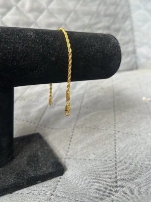 Tunt guldarmband med tvinnad kedja - Snyggt och stilrent armband i guldfärgad metall med tvinnad kedja. Armbandet har en enkel karbinhake som lås och passar perfekt för dig som gillar minimalistiska accessoarer. Lätt att matcha med andra smycken och ger en elegant touch till din stil. 20cm. Checka min profil för passande halsband.