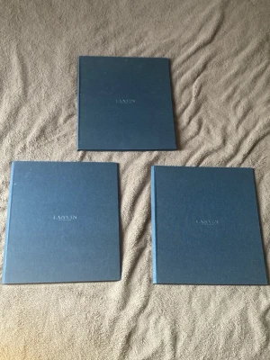 Blåa Lanvin konstböcker - En av blckena har inga papper i sig. Dessa kommer från en butik som min pappa ägde förr där dem sålde designer kläder. Säljer tre exklusiva konstböcker från Lanvin med hårda blå omslag och stilren design. Böckerna innehåller bilder och texter om Lanvins herrkollektion, bland annat vår/sommar 2009. Perfekt för modeintresserade och samlare.