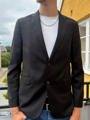 Kavaj Oscar Jacobson (svart) - Säljer nu en hög kvalitets kavaj från Oscar Jacobson i mycket gott skick. Passar till arbete, dop, bröllop och andra formella tillfällen!🤗 Säljs tyvärr inte längre, men nypris låg på ca 6000-8000kr  Modell: Falk Suit Style: 2100 Quality: 9484 Färgkod: 311 (svart) Storlek: 154  Storlek 154 motsvarar ungefär: * EU 54 i vidd * Längd omkring 185–195 cm * Bröstmått omkring 108 cm  Mått Längd: 81 cm Bredd: 51 cm Armlängd: 72 cm  Färg: Svart Material: 100% Ull  Självklart rollas plagget innan leverans❗️