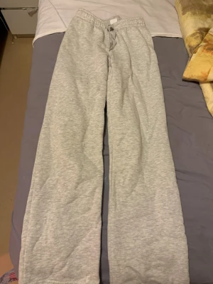 Grå mjukisbyxor med raka ben - Ett par klassiska grå mjukisbyxor med raka ben och resår i midjan samt dragsko. Perfekta för chill dagar hemma eller när du vill vara extra bekväm. Tillverkade i mjukt och skönt material.