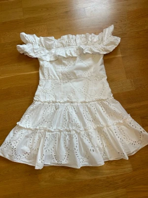  Slutsåld Vit offshoulder klänning från Zara - Superfin vit offshoulder klänning från Zara med volangdetaljer och broderade spetsmönster. Klänningen har en kort, utställd modell med flera lager och romantisk känsla. Perfekt för sommarens alla tillfällen!