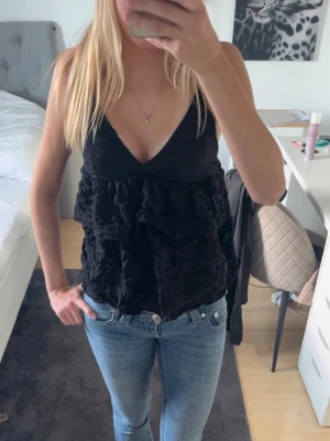 Svart volang topp med v-ringning - Säljer en svart topp med v-ringning och volangdetaljer i storlek S från Gina Tricot. Aldrig använd, helt ren!