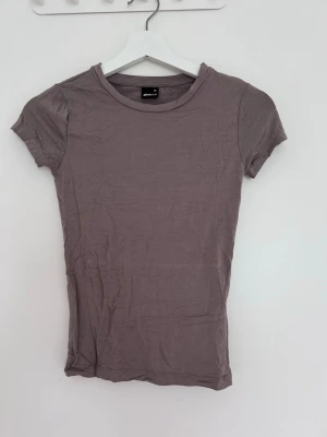 Ljusbrun basic t-shirt - En enkel ljusbrun t-shirt med rund hals och korta ärmar. Modellen är figurnära och passar perfekt till jeans eller kjol. Tillverkad i mjukt bomullsmaterial för en bekväm känsla hela dagen.