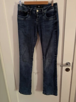 Blå bootcut jeans från LTB - Snygga blå bootcut jeans från LTB med klassisk femficksdesign. Jeansen har låg midja och är tillverkade i stretchigt denim för en bekväm passform. Perfekta för dig som gillar en tidlös och avslappnad stil. Storlek: 26/32