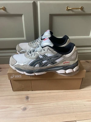 Asics GEL NYC Grå  - Asfeta skor från Asics i en mixad grå färg med röda detaljer | Riktigt eftertraktade trainers | Modell: GEL NYC | EU 43 1/2 | Använda men i mycket gott skick, box & tags medföljer 🤟
