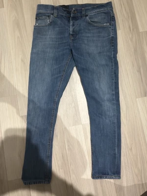 Blå slim jeans DONDUP - Säljer ett par klassiska blå jeans som är slim och fem fickor. Jeansen har en snygg tvättad look och stängs med dragkedja och knapp. Perfekta till vardags och passar till det mesta. Materialet är denim i bomull. DONDUP 