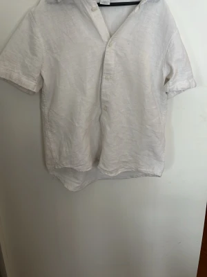 Vit linneskjorta från Lindex Kids - Klassisk vit skjorta från Lindex Kids i luftig linnemix. Skjortan har korta ärmar, knappar framtill och en avslappnad passform. Perfekt till sommarens alla tillfällen och enkel att styla med jeans eller shorts.