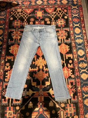Ljusblå raka jeans från Diesel - Snygga ljusblå jeans från Diesel med klassisk femficksdesign och raka ben. Jeansen har en något tvättad look och är tillverkade i denim. Perfekta för en avslappnad stil.