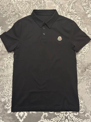 Moncler T-shirt Pike - Fin stilren klassisk Moncler pikétröja T-shirt som ny använd en gång bara. Stilren krage och ikonisk logotyp broderad på bröstet. Tillverkad i mjuk bomull för en bekväm känsla och snygg passform, pris kan diskuteras vid snabb affär.
