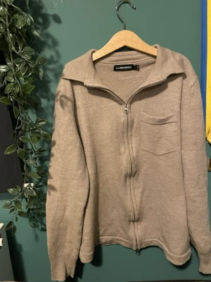 Beige ziptröja från J.Lindeberg - Snygg beige ziptröja från J.Lindeberg med krage och bröstficka. Tröjan har långa ärmar, ribbade muddar och är tillverkad i mjukt material. Perfekt för lager på lager och enkel att matcha med olika outfits.