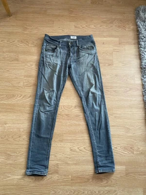 Slim fit grå jeans från Tiger of Sweden - Säljer ett par grå slim fit jeans från Tiger of Sweden. Jeansen har klassisk femficksmodell, normalhög midja och smala ben. Materialet är mjukt denim med lätt tvättad look och snygga slitningar. Perfekta för en avslappnad och trendig stil.
