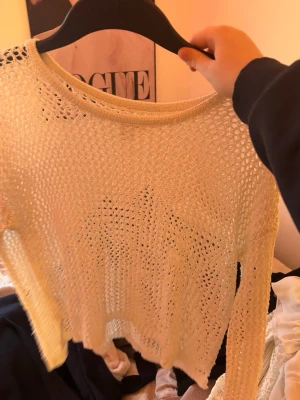 Beige stickad meshtröja Suiteblanco - Trendig beige stickad meshtröja från Suiteblanco. Tröjan har lång ärm, rund halsringning och är gjord i ett luftigt, genomskinligt material med hålmönster. Perfekt att styla över ett linne eller crop top för en cool lager-på-lager-look.