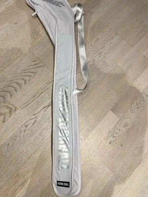 Vit innebandyfodral från Zone Floorball - Snygg vit innebandyväsk från Zone Floorball med silverfärgad axelrem och tryck i vitt och silver. Passar till klubbor upp till 92 cm. Oanvänt, säljer pga min klubba är för lång