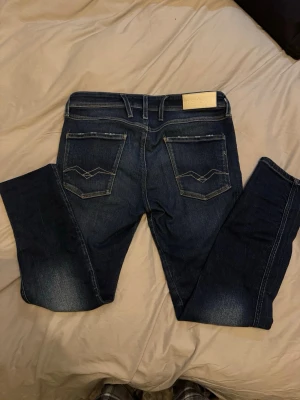 Replay ambass - Snygga mörkblå jeans från Replay med klassisk femficksmodell och dekorativa sömmar på bakfickorna. Jeansen har en smal passform och är tillverkade i stretchigt denimtyg för extra komfort. Perfekta för dig som gillar en stilren och modern look. W31 L30
