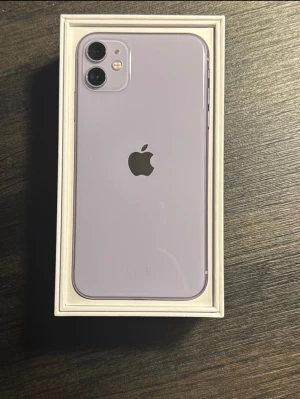 Lila iPhone 11 128gb - Säljer en snygg lila iPhone 11 med stilren design och rundade kanter. Baksidan är i glas och har två kameror samt Apple-loggan i mitten. Telefonen har en stor skärm och levereras i originalkartong. Är i bra skick och har 128gb