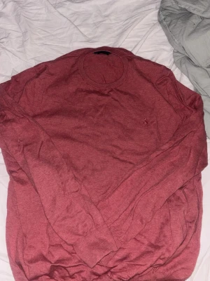 Mörkröd tröja polo - Slim. Säljer en mörkröd polo långärmad tröja med rund halsringning och diskret broderad logga på bröstet. Tröjan har ribbade muddar vid ärmslut och nederkant. Perfekt för dig som gillar enkel men stilren design.