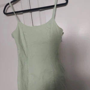 Ljusgrön kort klänning från Gina Tricot - Superfin ljusgrön klänning från Gina Tricot med smala axelband och figurnära passform. Klänningen har dragkedja i sidan för enkel påklädning och är perfekt för sommarens varma dagar.