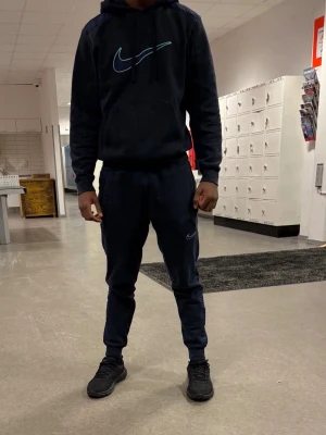 Svart Nike hoodie med turkos logga - Snygg svart hoodie från Nike med stor turkos logga på bröstet. Klassisk känguruficka framtill och justerbar huva med snören. Tillverkad i mjukt material som passar perfekt till streetwear och chill dagar. Pris kan ej diskuteras, skriv för mer frågor eller bilder bara om ni tänker på att köpa!!