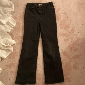 Svarta bootcut jeans - Säljer ett par svarta bootcut jeans med hög midja och klassisk femficksdesign. Jeansen har vida ben och är tillverkade i ett mjukt denimtyg. Perfekta för dig som gillar en retro och avslappnad stil.