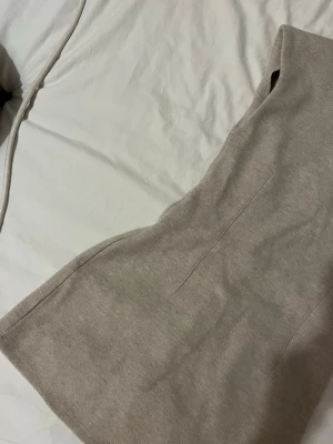 Beige stickad klänning från Zara - Snygg beige stickad klänning från Zara med rund halsringning och ärmlös design. Klänningen har en rak och enkel passform som ger en stilren look. Perfekt att styla med boots eller sneakers för en trendig outfit.