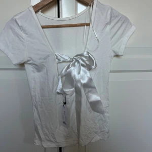 Vit topp med rosett  - Supersöt vit topp ifrån lager 157 med öppen rygg och en rosett som man knyter! Helt ny med lappen kvar💕