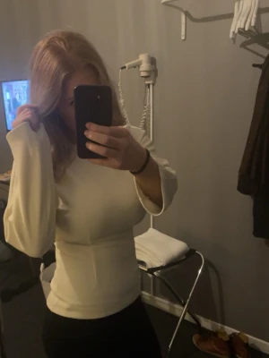 Vit långärmad topp med markerad midja - Säljer en stilren vit topp med långa ärmar och markerad midja. Köpt på NK nypris 2000kr 