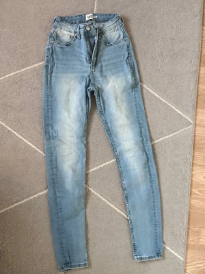 Snake jeans stretch - Säljer ett par ljusblå skinny jeans från 157 med klassisk femficksmodell och dragkedjegylf. Jeansen har en snygg tvättad look och smal passform som sitter tajt längs benen. Perfekta till en avslappnad stil och lätta att matcha med olika toppar.