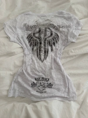 Harley-Davidson t-shirt - Säljer en vit t-shirt från Harley-Davidson med coolt tryck av vingar och logga på bröstet. Detaljerna är i silver! Köpte den på en second hand butik i Italien för ca ett år sen men har endast använt den typ två gånger själv! 