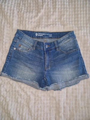 Blå denimshorts low waist Cubus - blå denimshorts från Cubus med låg midja och råa kanter. Klassisk femficksmodell med knapp och dragkedja framtill. Perfekta till sommaren och lätta att matcha med olika toppar. Sitter jätte fint 🍑😍🌺