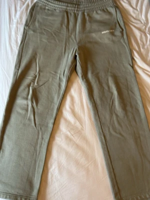 Gröna mjukisbyxor från Arigato - Snygga gröna mjukisbyxor från Arigato med tryck vid fickan. Byxorna har resår i midjan och raka ben. Perfekta för chill dagar och har en enkel, clean look. Materialet känns mjukt och bekvämt mot huden.