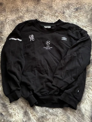 Umbro Champions League tröja - Svart sweatshirt från Umbro med Champions League-tryck och Chelsea FC-logga på bröstet. Storlek XL men sitter mer som M 🖤