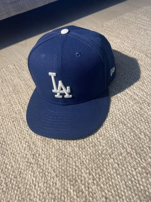 Mörkblå MLB new era keps - Snygg mörkblå keps från MLB med klassisk passform och vit knapp på toppen. en broderad MLB-logga baktill. Tillverkad i bomullstyg som andas.