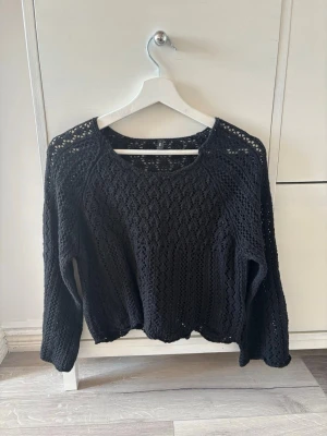 Svart stickad tröja från ONLY - Snygg svart virkad stickad tröja från ONLY med rund halsringning och lång ärm. Tröjan har ett luftigt, hålmönstrat material som ger en trendig look och passar perfekt till lager på lager-stil. Enkel att matcha med både jeans och kjol. Aldrig använd💕