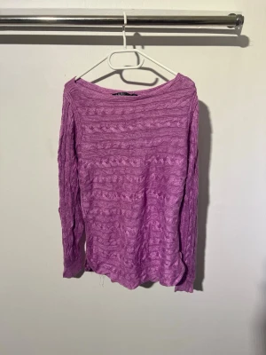 Lila kabelstickad tröja lauren Ralph Lauren  - Säljer en lila kabelstickad tröja med rund halsringning och långa ärmar. Tröjan har ett vågigt mönster och är tillverkad i ett mjukt, tunt material som passar perfekt för lager på lager. Enkel och snygg design som är lätt att matcha.