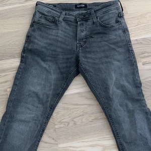 Grå jeans från Jack & Jones. Size 30/30 - Snygga grå jeans från Jack & Jones med klassisk femficksmodell och raka ben. Jeansen har en tvättad look för en avslappnad stil. Tillverkade i bomull med lite stretch för extra komfort. Ny skick!